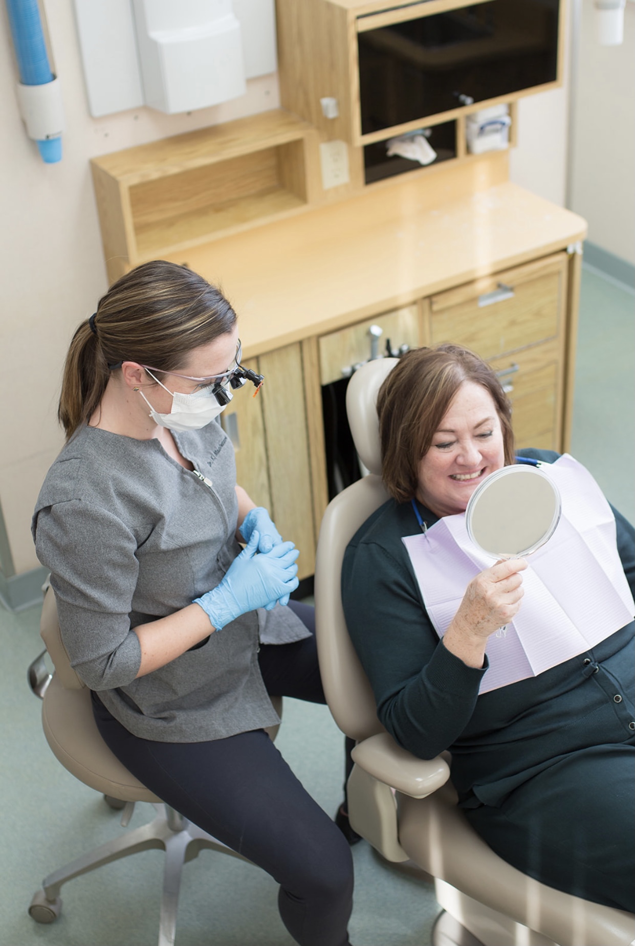 Dentist with patient looking at teeth in mirror